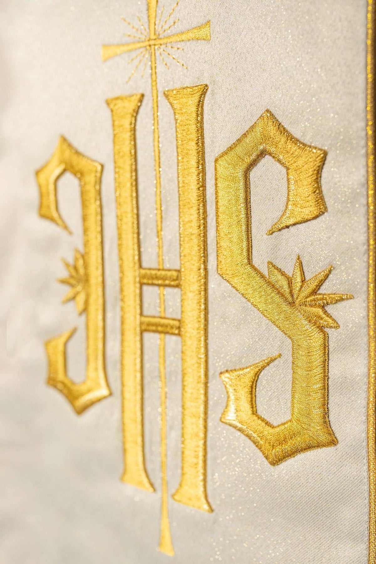 Gold chasuble close-up showing embroidered IHS motif on the wide orphrey