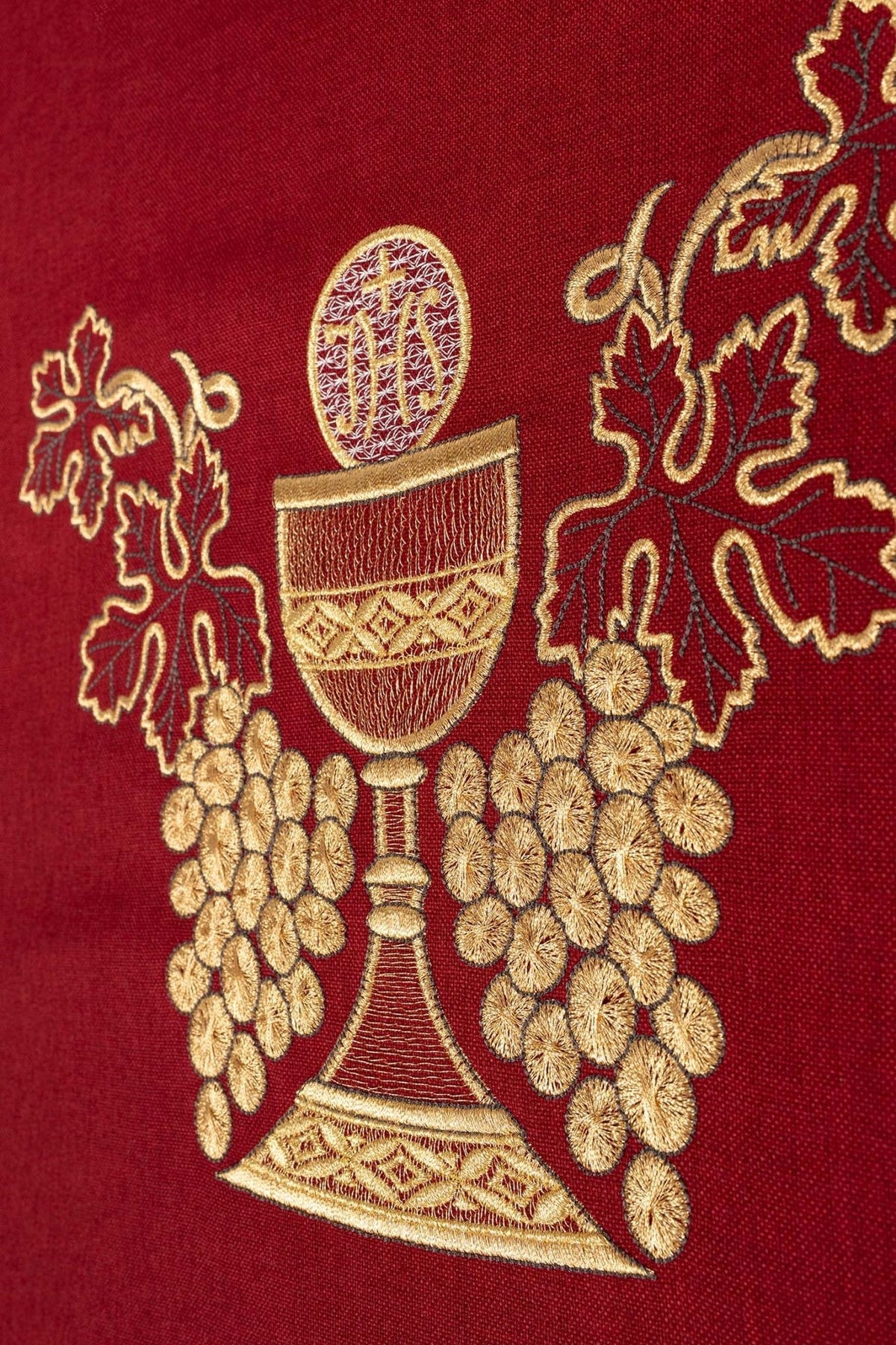 Red embroidered chasuble detail showing gold chalice, grapes and embroidery