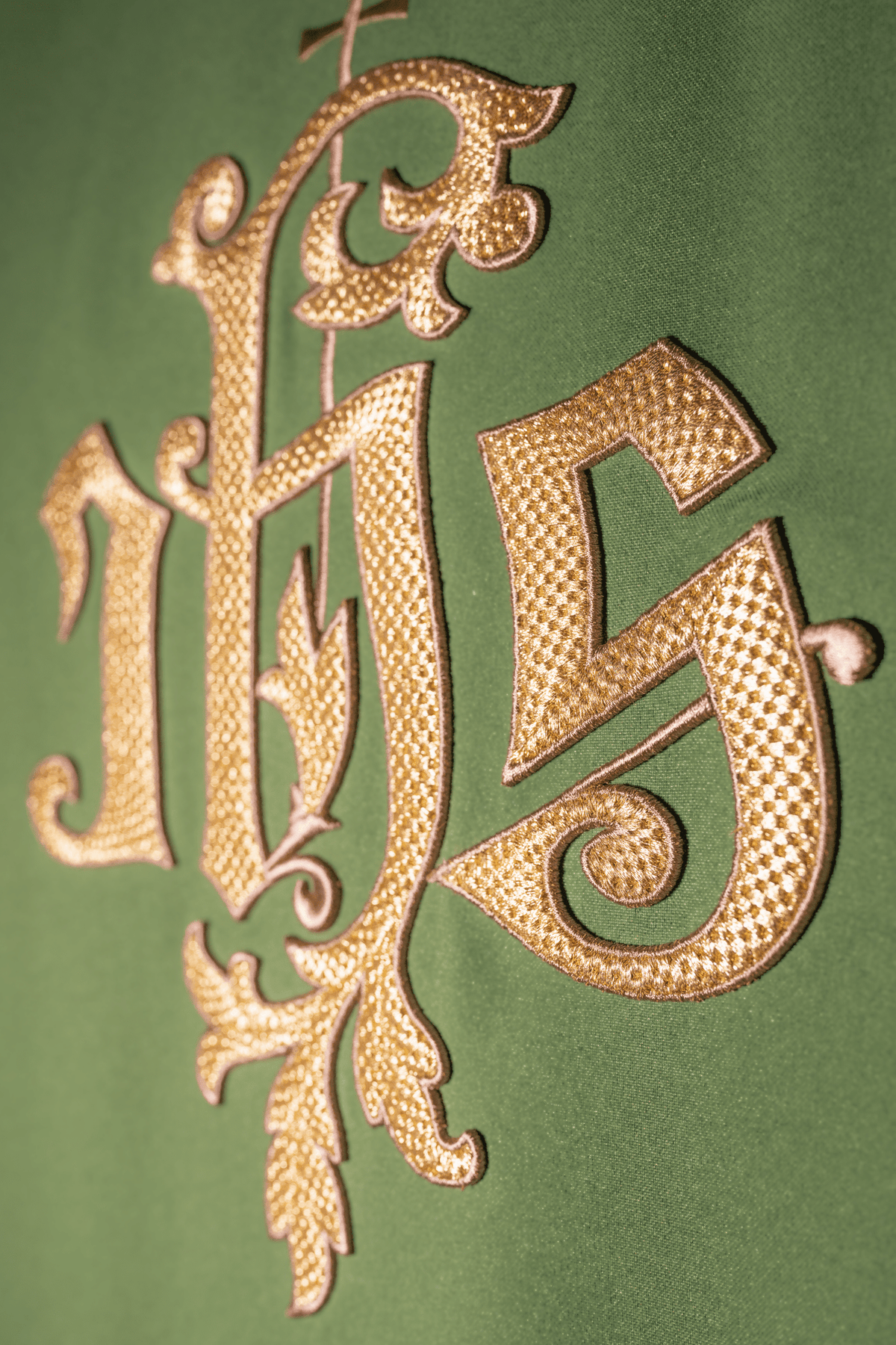 Green chasuble close-up showing gold IHS embroidery on green satin