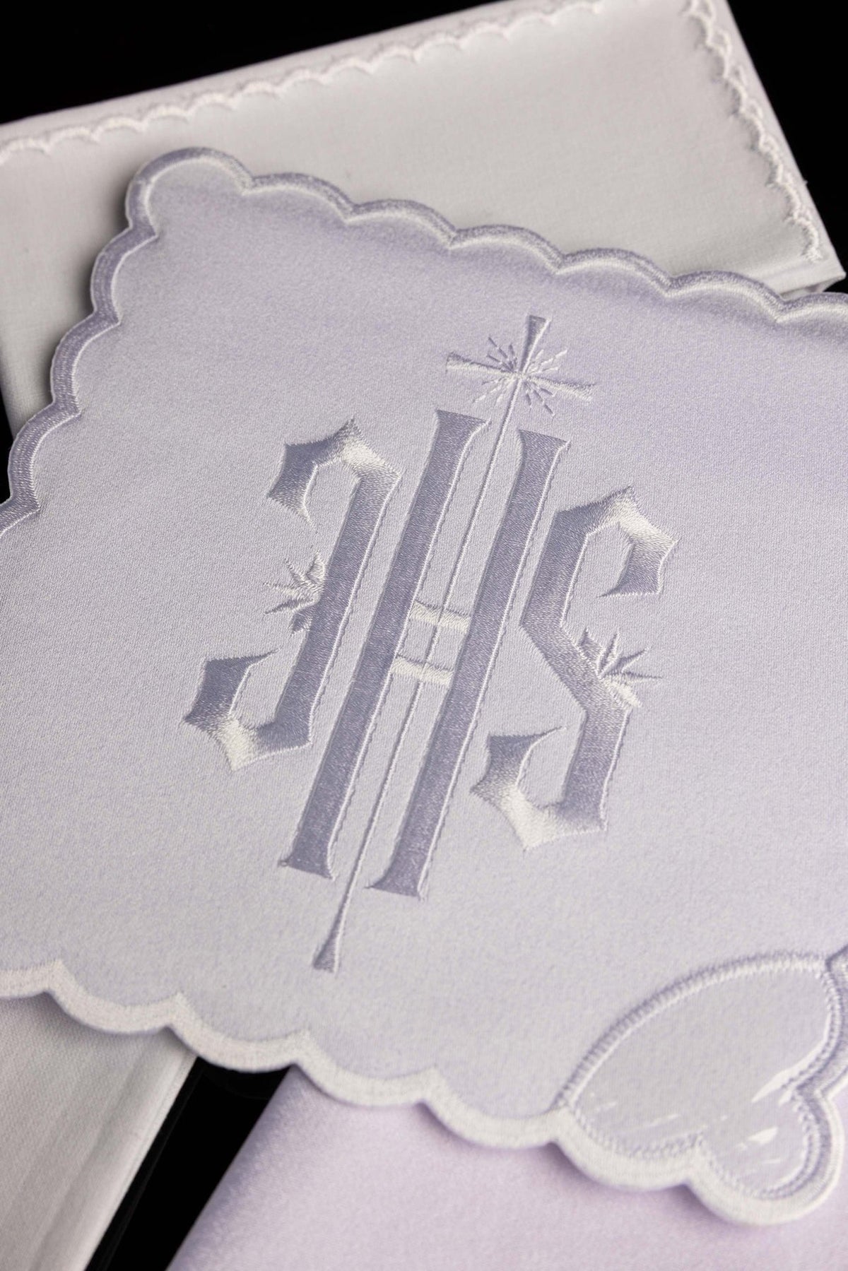 Altar linen set close-up showing white embroidered IHS monogram and scalloped trim