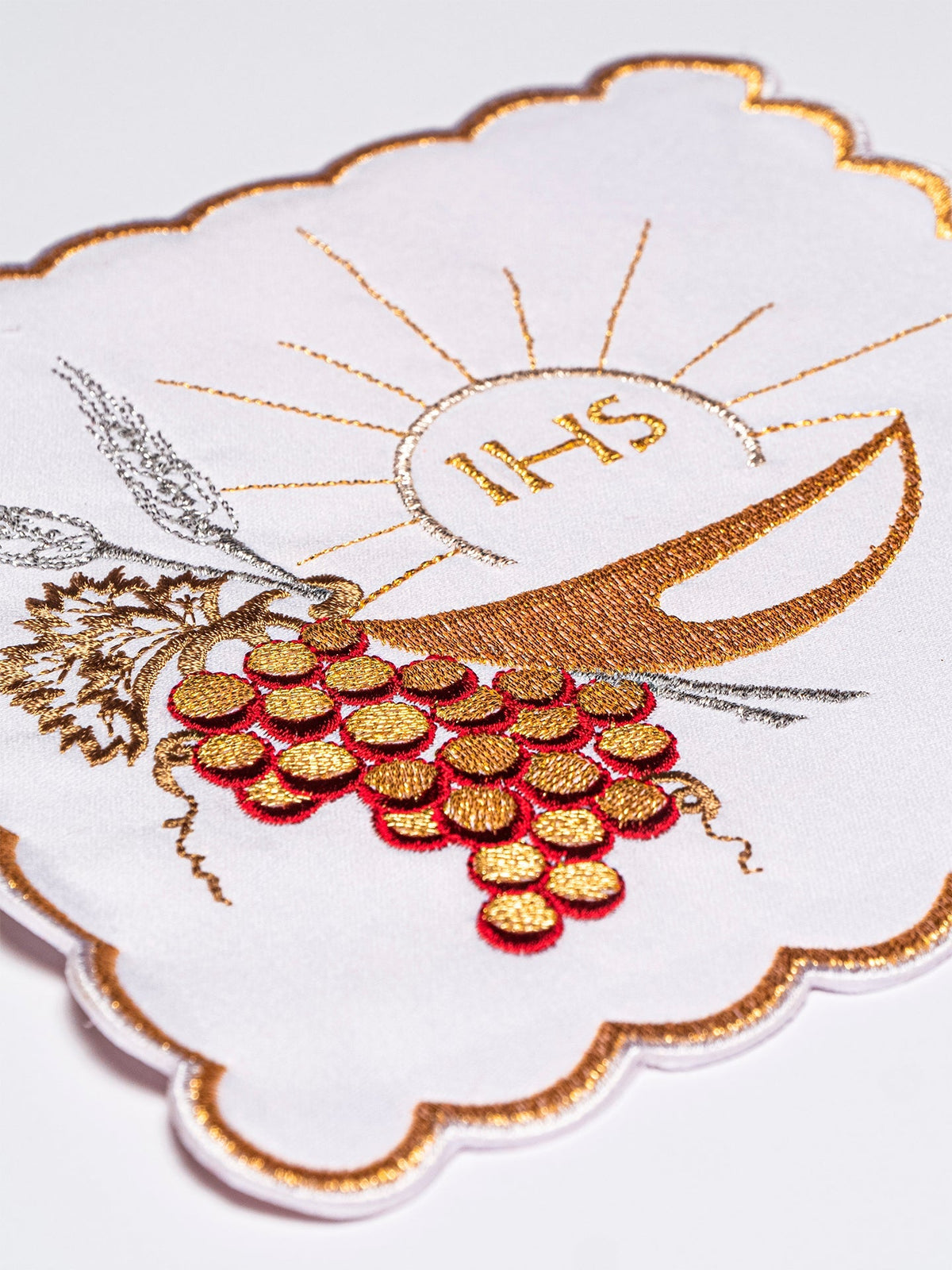 Altar linen set close-up with embroidered gold chalice, IHS, grapes and wheat on white fabric