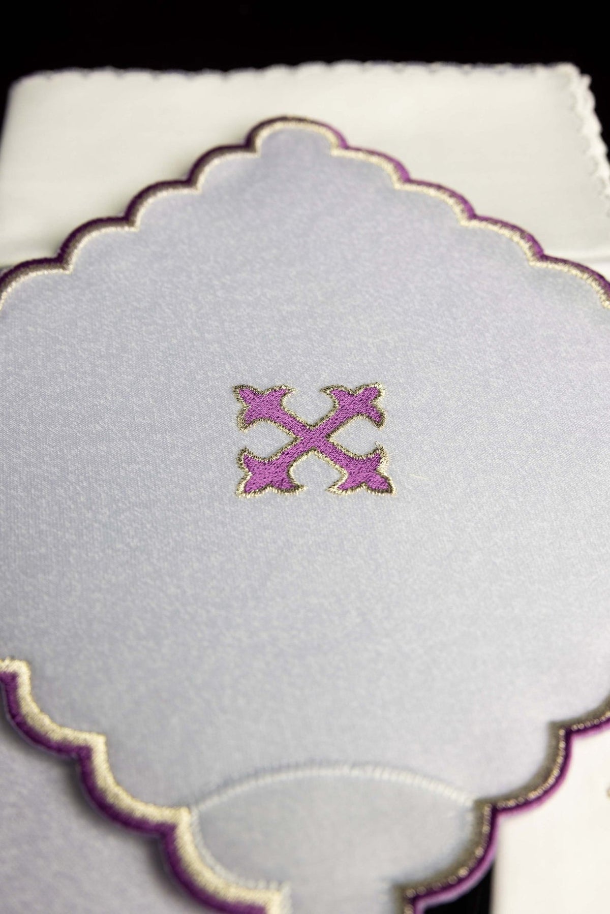 Altar linen set close-up with embroidered purple cross and scalloped purple-and-gold edging