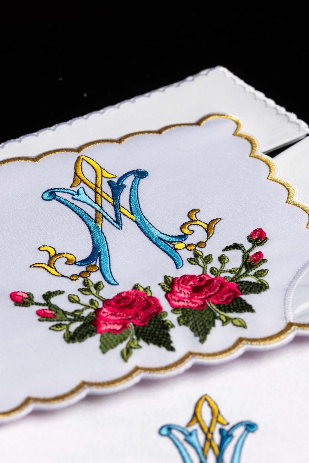 Altar linen set close-up showing blue and gold Marian symbol with embroidered pink roses