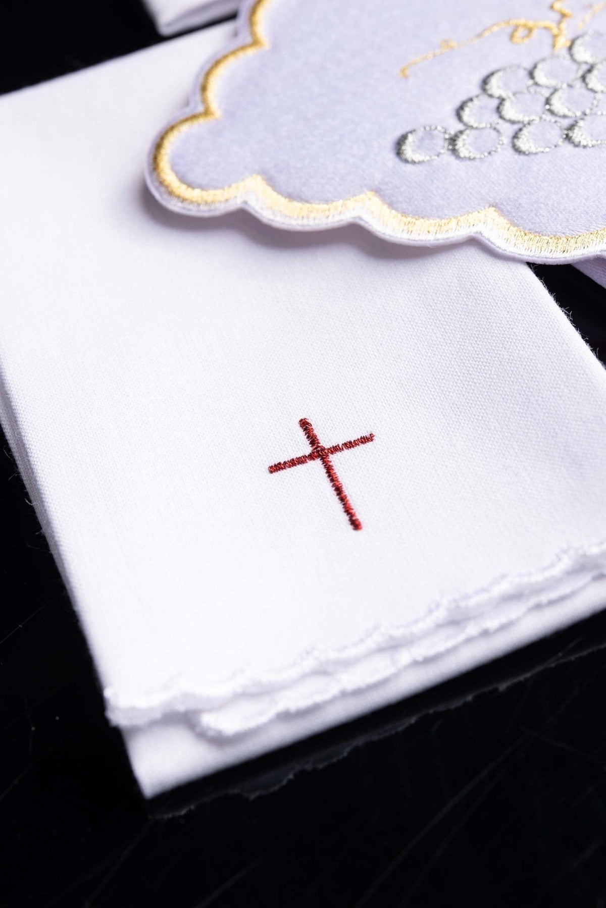 Altar linen set detail showing white folded linen with red cross embroidery