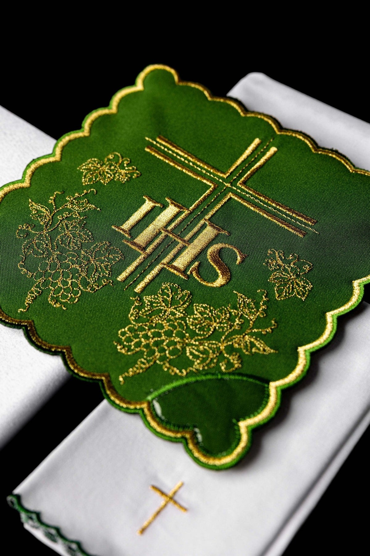 Green embroidered cloth detail with gold IHS, cross and grape motifs