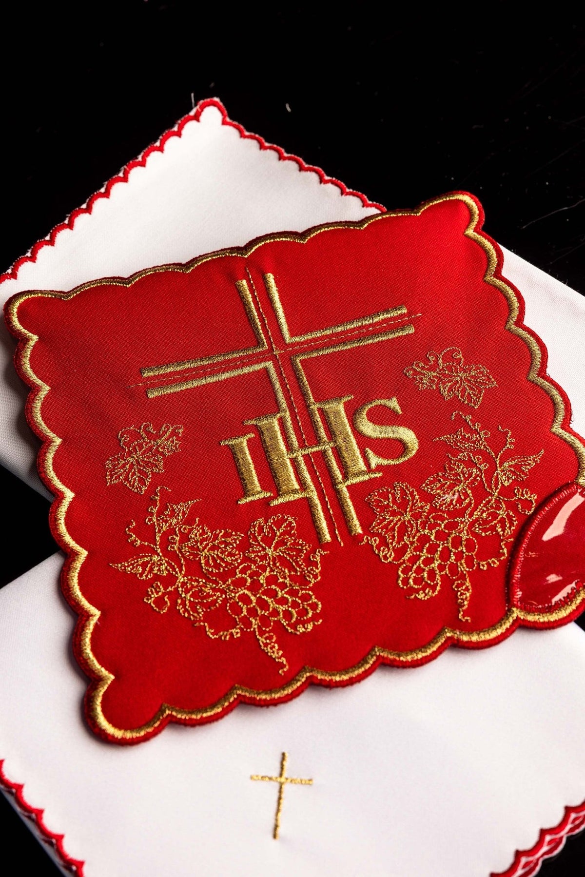 Altar linen set close-up showing red cloth with gold IHS, cross and grape embroidery