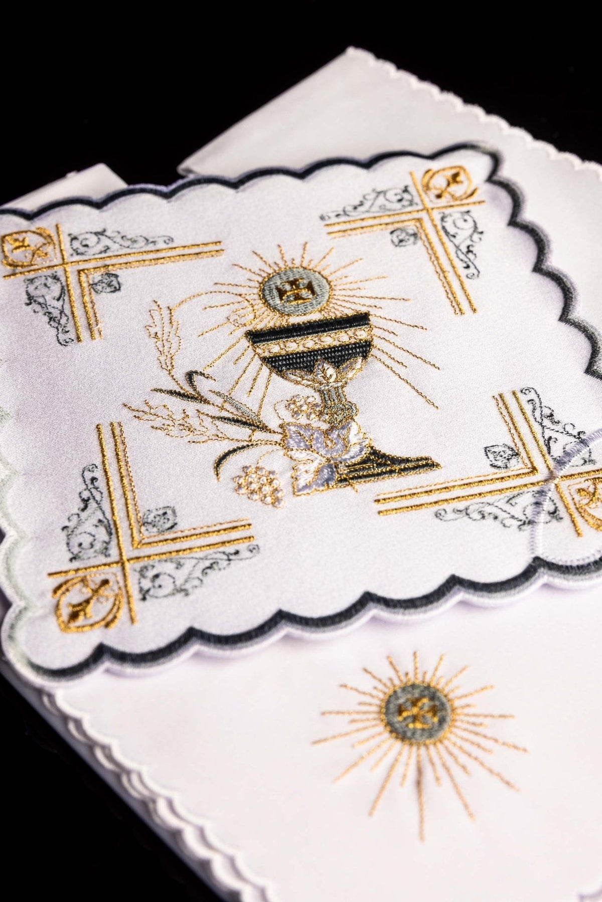 Altar linen set detail showing embroidered gold and silver chalice motif with ornate corner designs