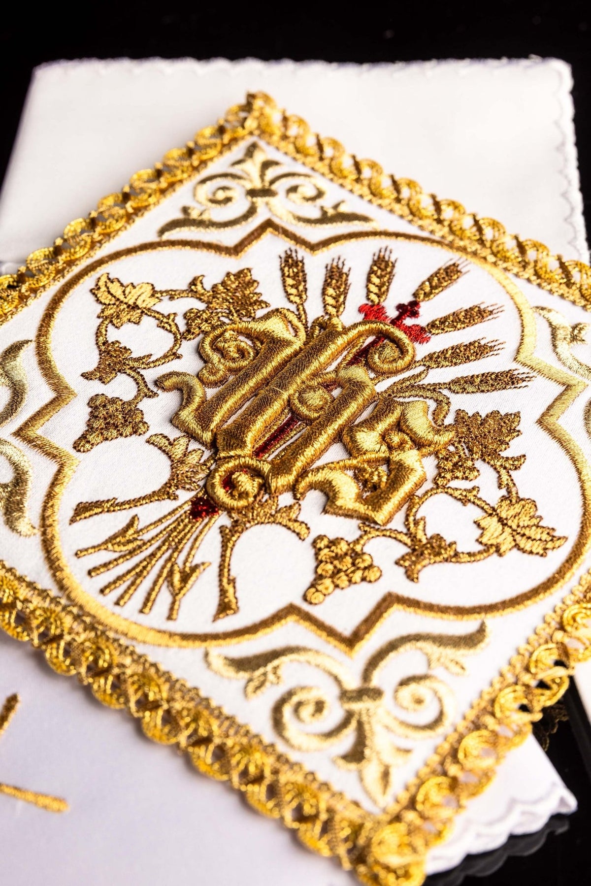Altar linen set detail showing raised gold IHS embroidery with wheat, vine and red accents