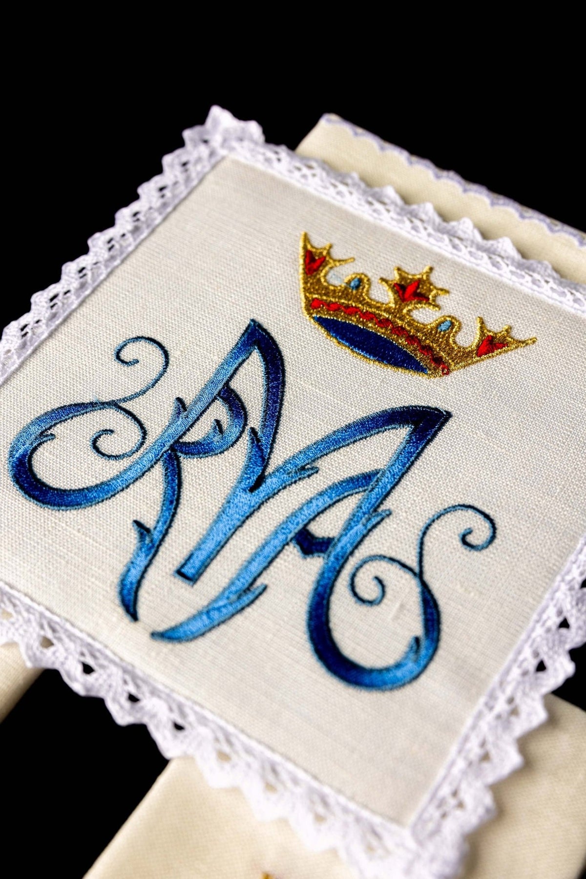 Altar linen set close-up showing embroidered blue Marian symbol and gold crown