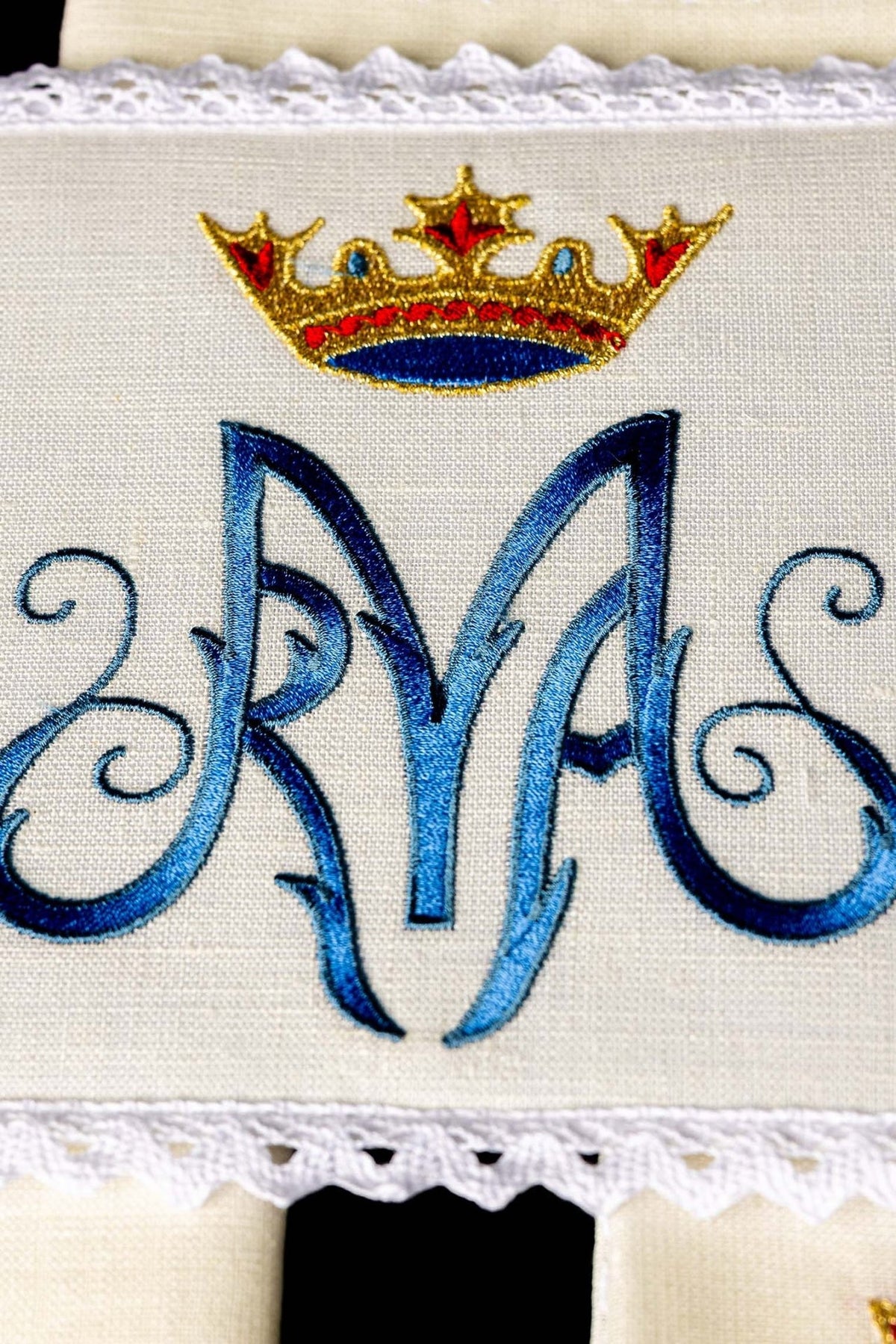 Altar linen set close-up showing blue embroidered Marian symbol and crowned motif