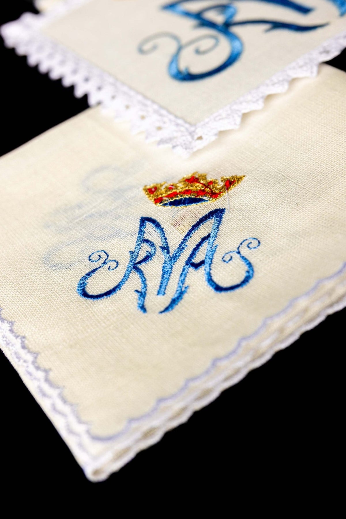 Altar linen set folded, showing embroidered Marian symbol and scalloped edging