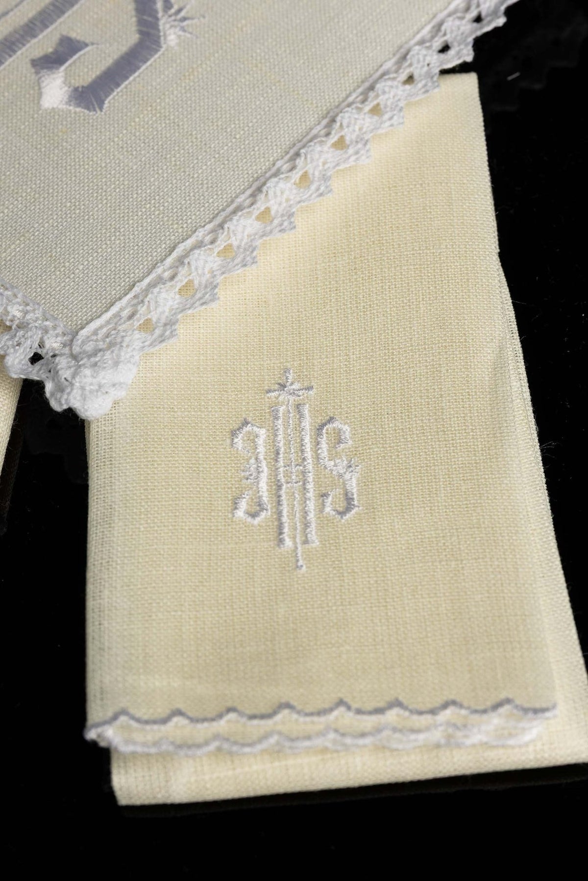 Altar linen set detail showing embroidered IHS motif on a folded white cloth