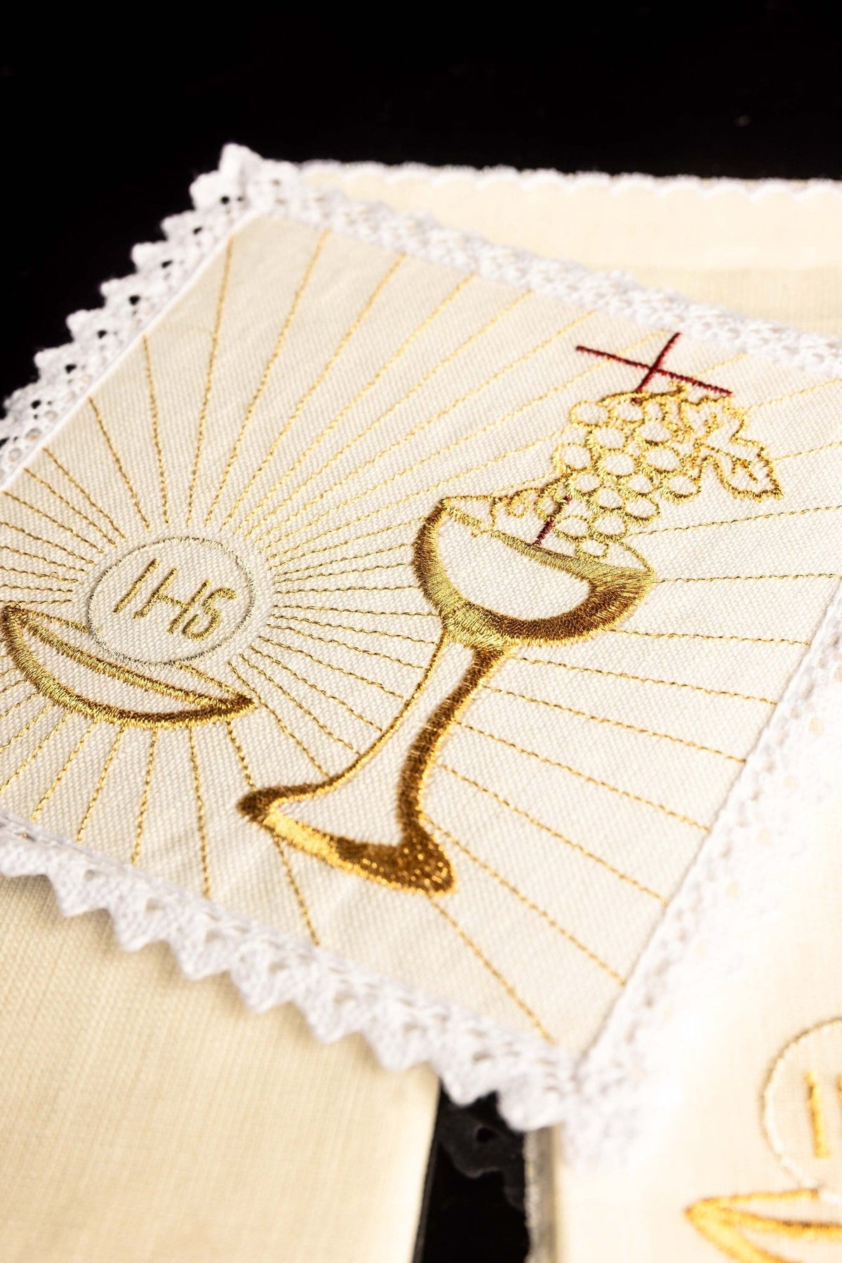 Altar linen set close-up showing embroidered gold chalice, grapes, cross and IHS host motif