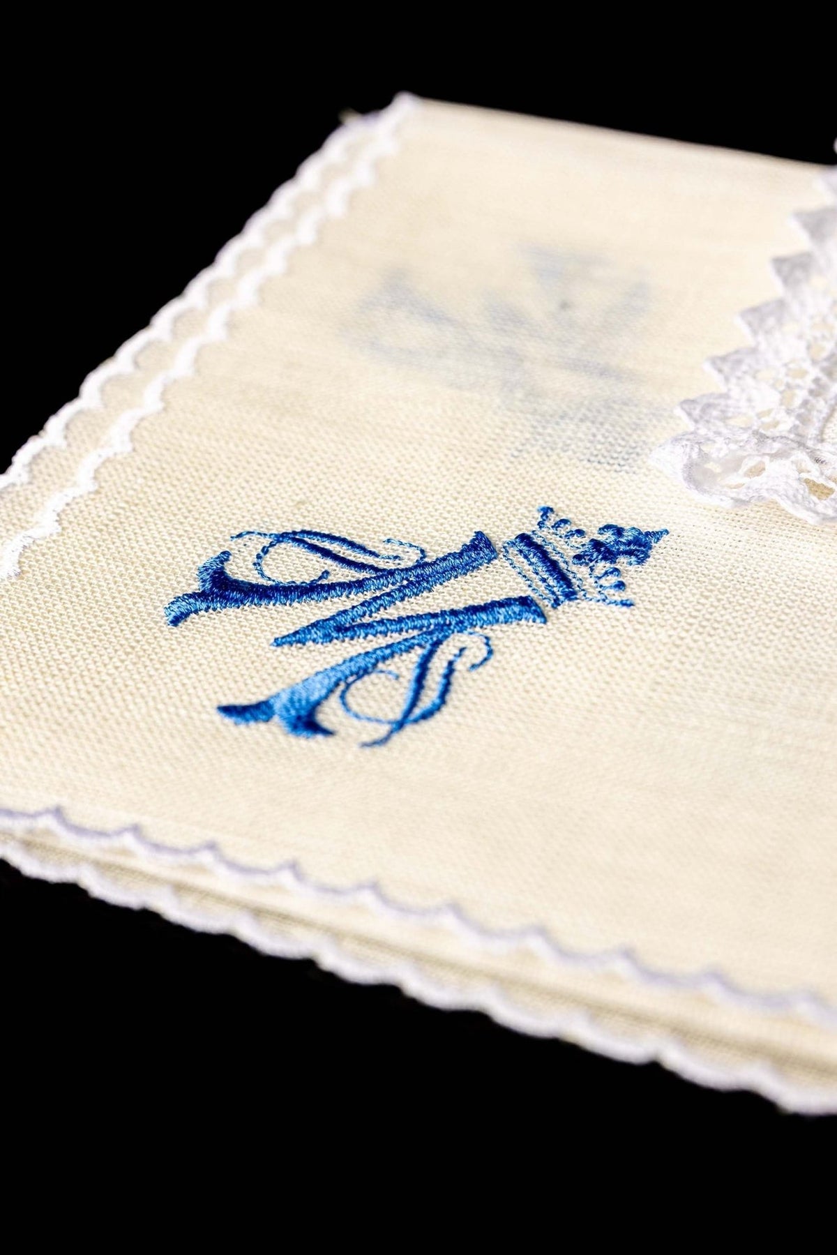 Altar linen set detail showing blue embroidered Marian symbol on cream linen with scalloped edging