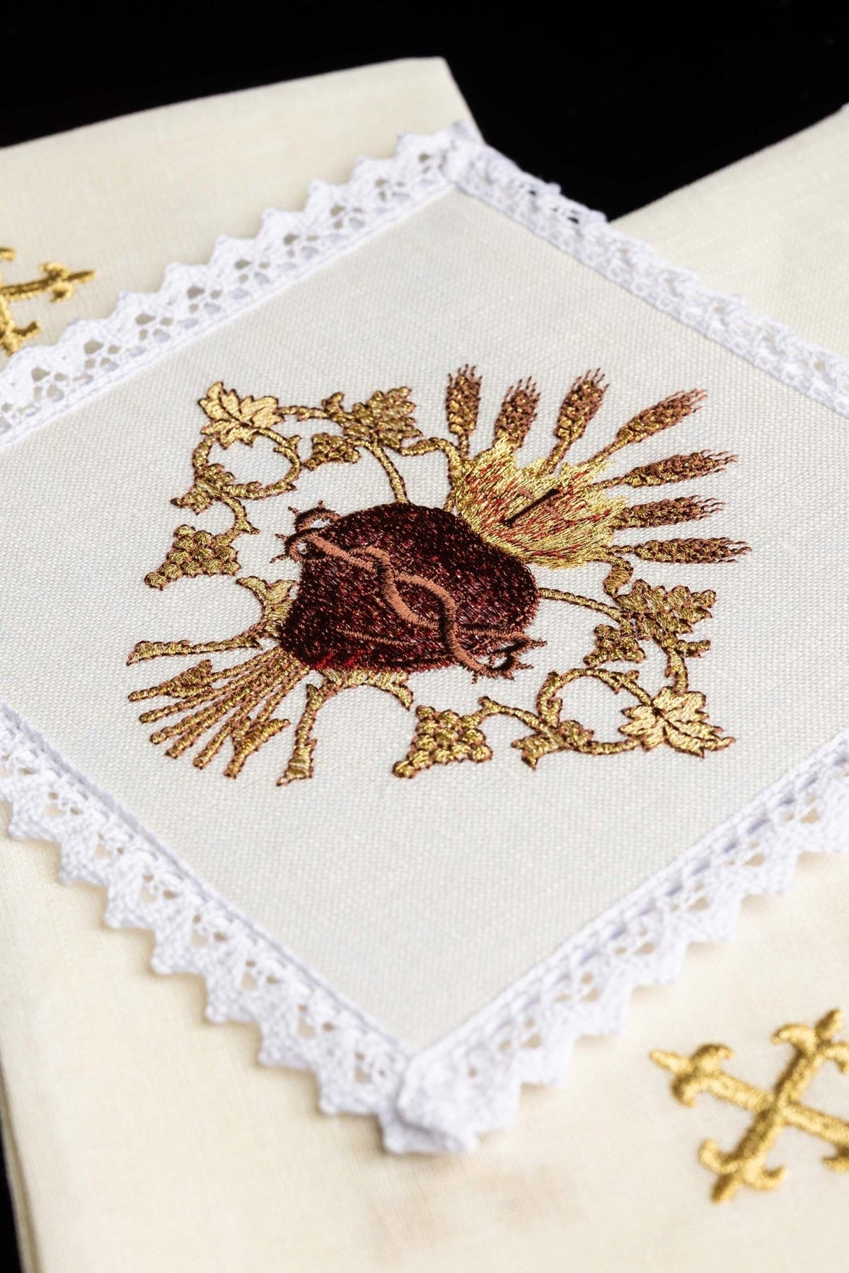 Altar linen set close-up showing the embroidered Sacred Heart of Jesus motif and lace border