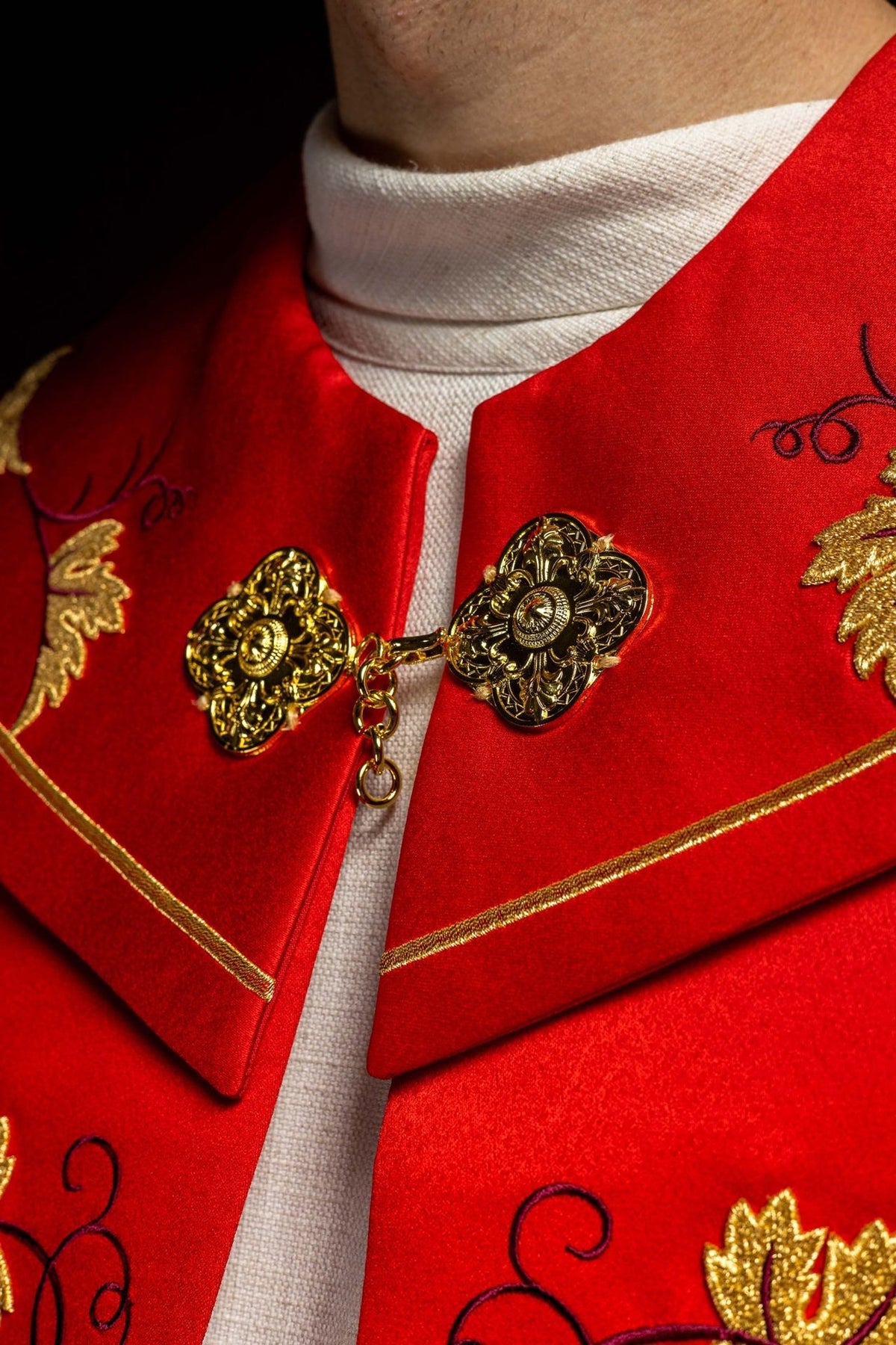 Red cope close-up of gold floral clasp and burgundy embroidery