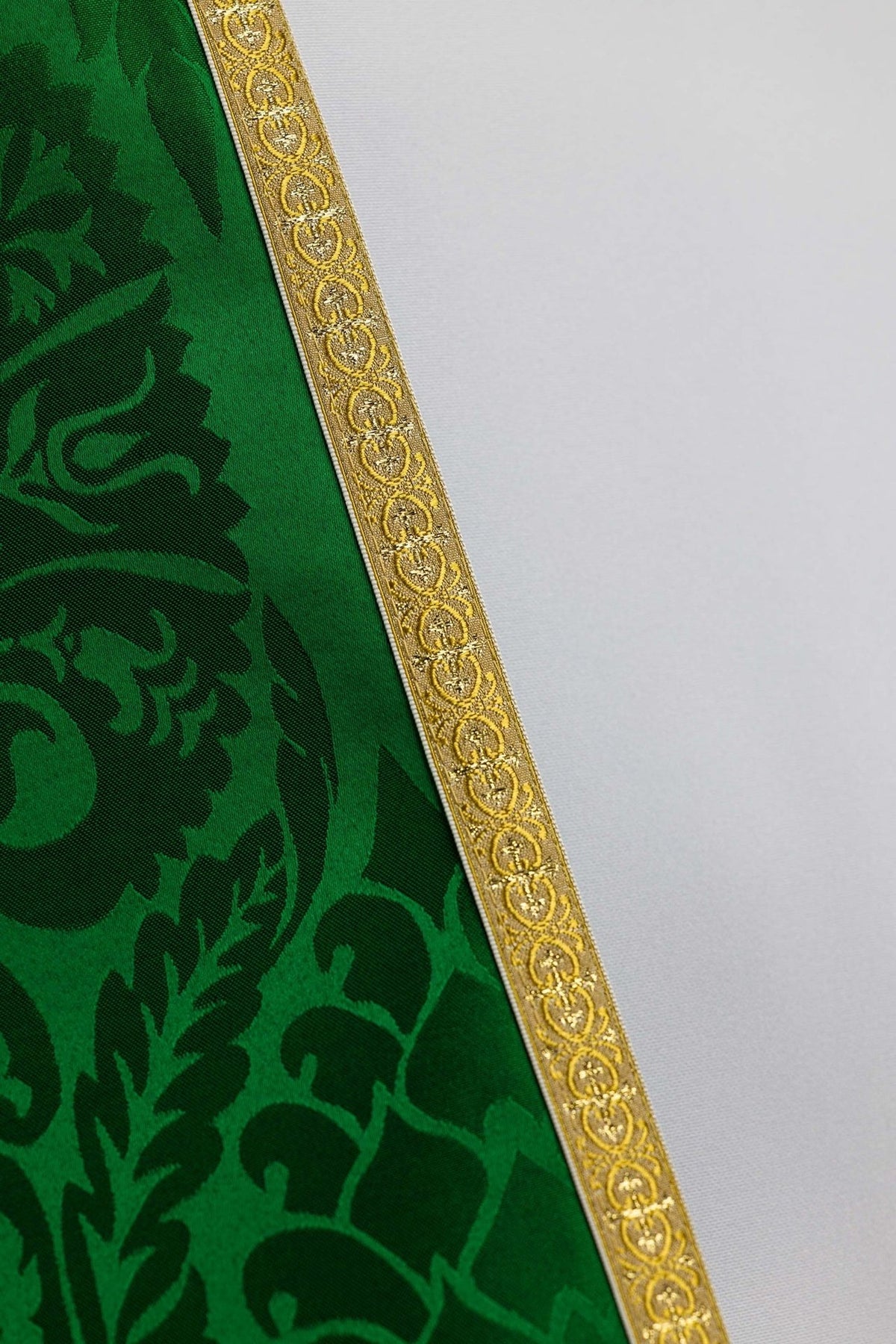 Green jacquard cope close-up showing ornate gold trim beside the ecru lining