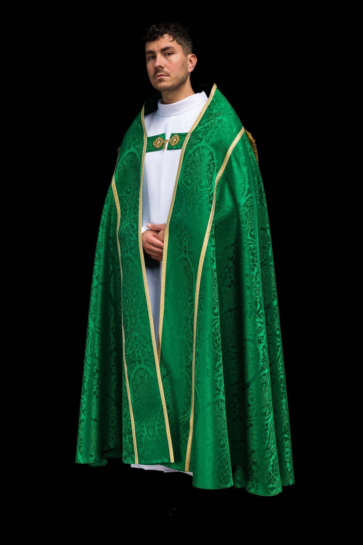 Green jacquard cope worn from the rear with a rounded gold-trimmed panel and fringe