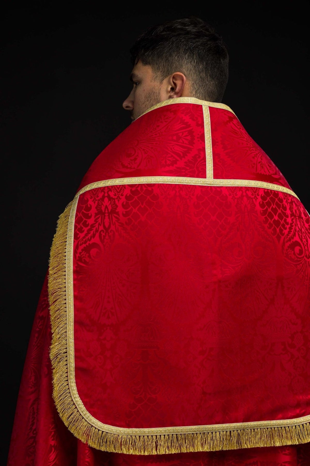 Red Roman cope back view with gold trim, patterned jacquard fabric and long gold fringe