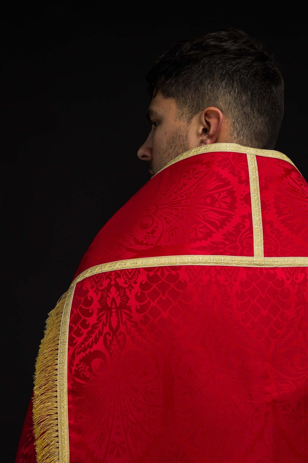 Red Roman cope back close-up with floral jacquard motifs, gold trim and fringe