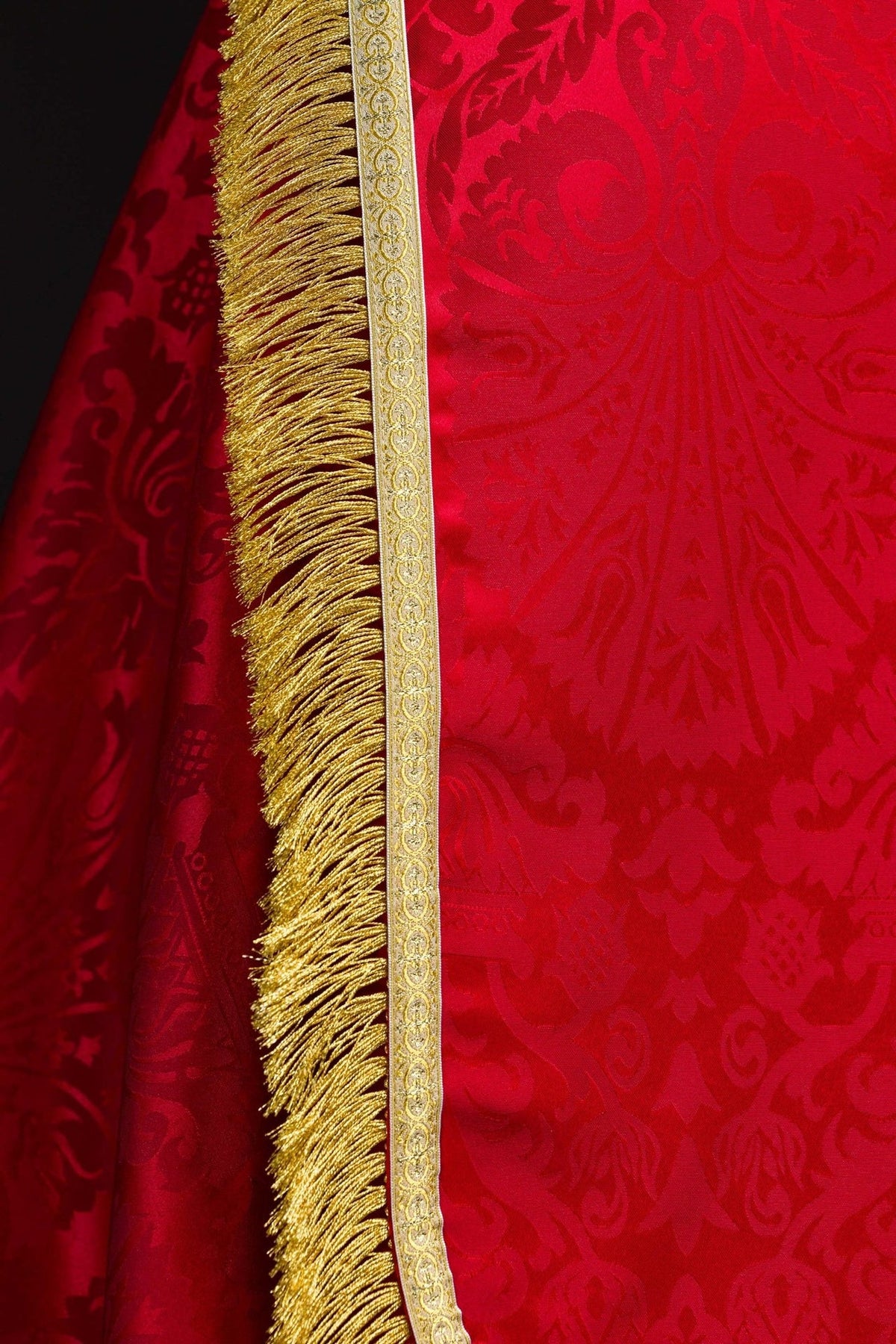 Roman cope detail showing red jacquard fabric, patterned gold edging and dense gold fringe