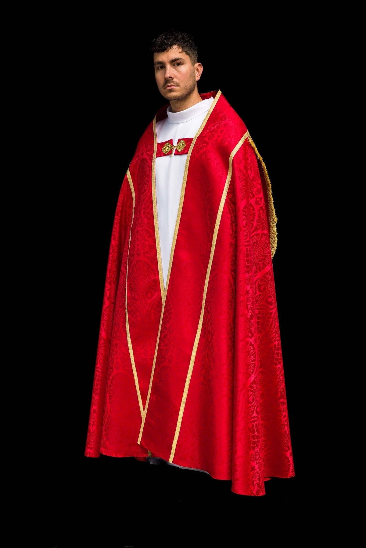 Red cope worn at an angle, showing gold-trimmed front, floral jacquard motifs and fringe