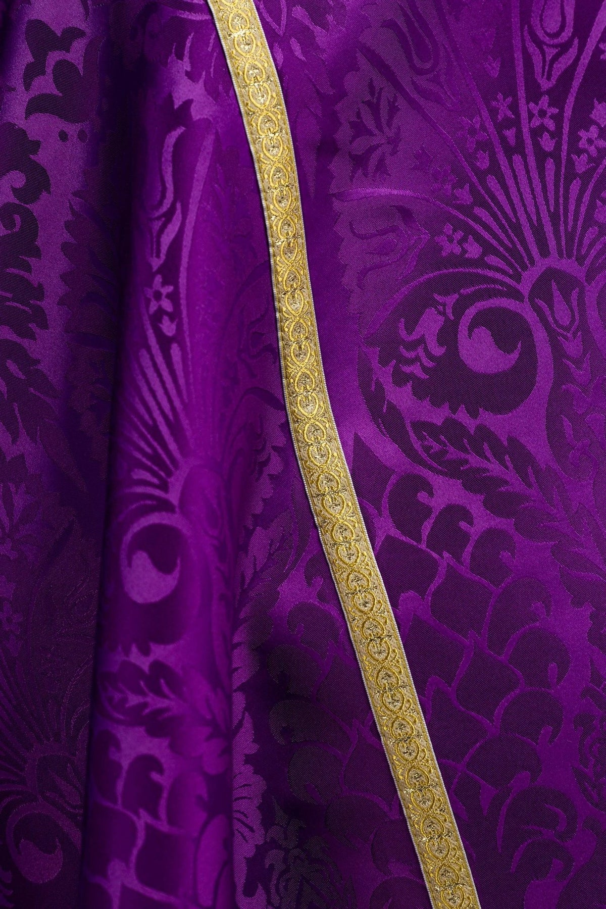 Purple cope close-up showing floral jacquard fabric and gold edging