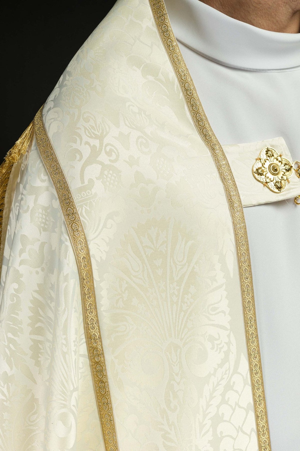Ecru cope close-up showing ornate jacquard motifs and gold trim