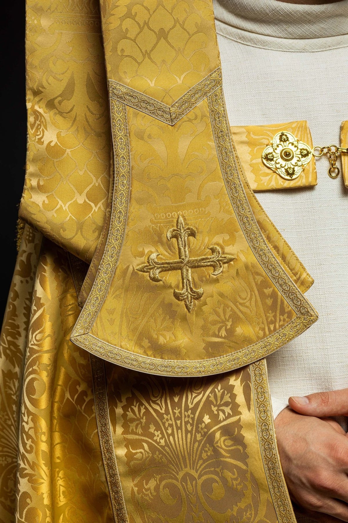 Gold cope close-up showing embroidered cross on the front panel and ornate trim