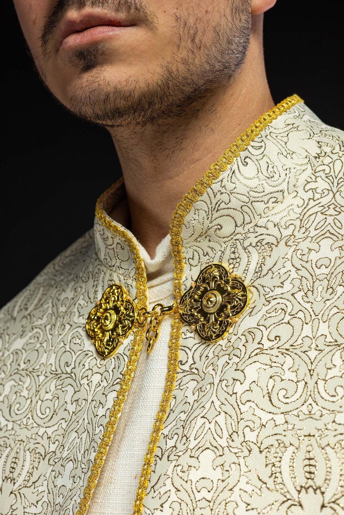 Ecru cope close-up showing ornate jacquard fabric and gold fasteners