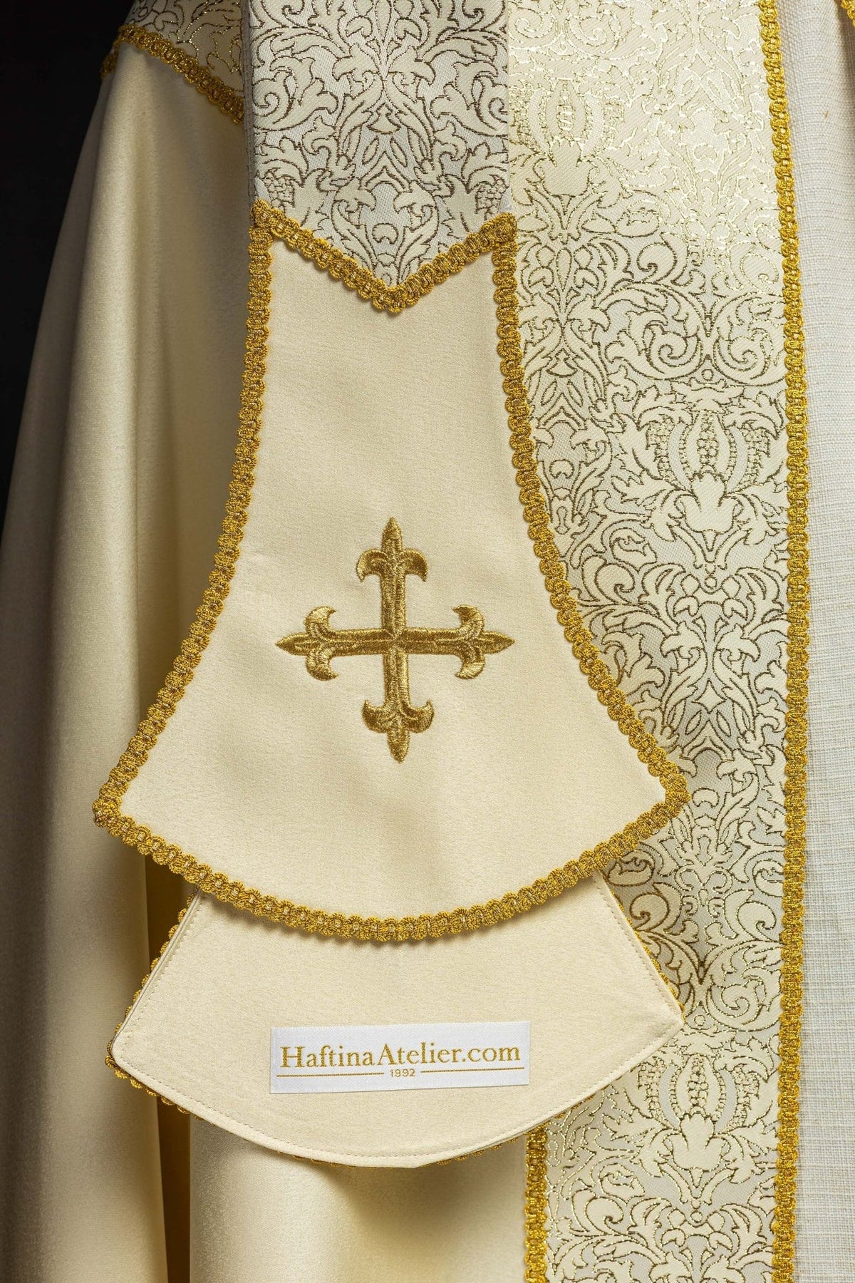 Ecru stole detail with embroidered gold cross and ornate trim