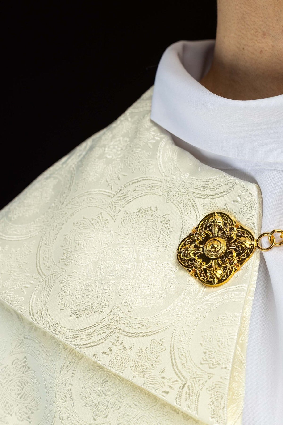 Ecru jacquard cope shoulder close-up with patterned fabric and gold clasp