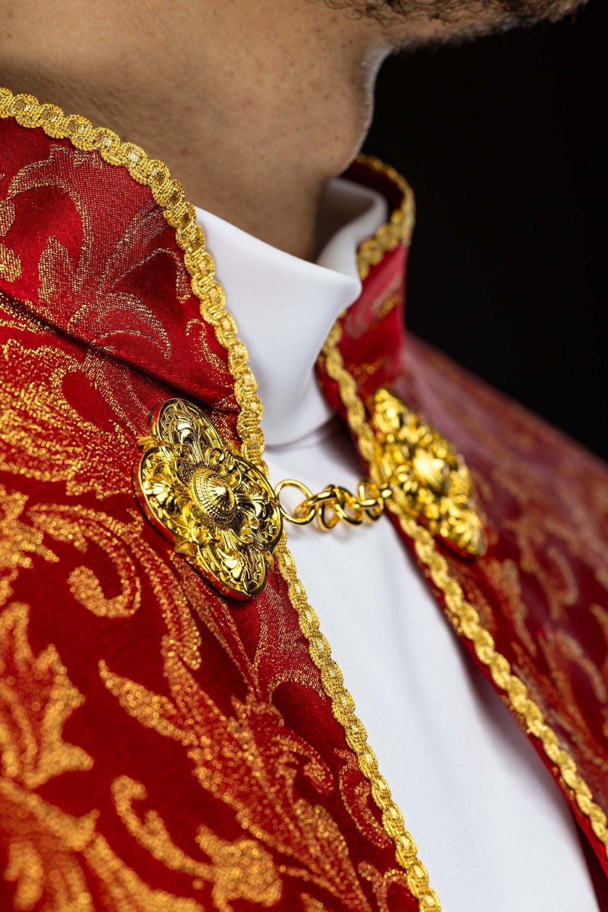 Red cope, close-up of gold clasp, floral jacquard fabric and trim