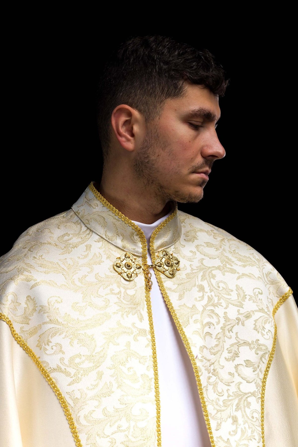 Ecru cope close-up showing jacquard fabric decoration, collar and gold clasp