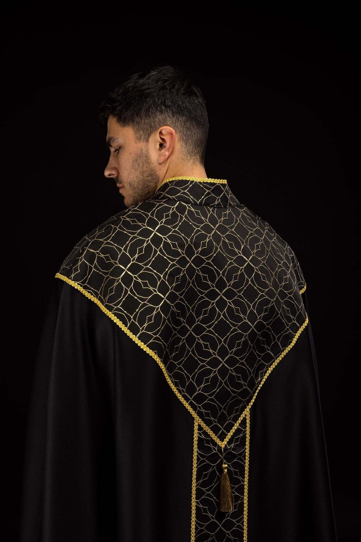 Black cope back view with gold embroidered floral pattern, trim and tassel