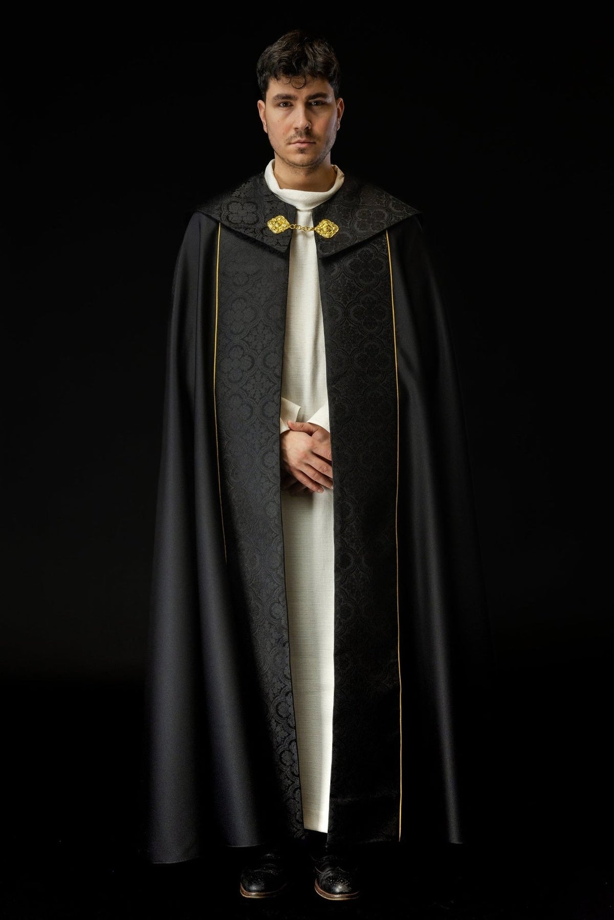 Black cope worn from the front, showing jacquard panels and gold trim