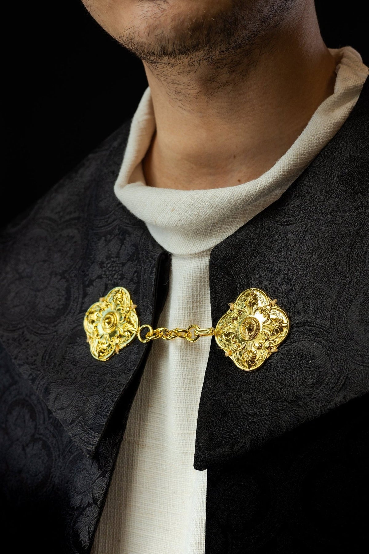 Black cope close-up with gold clasp and jacquard collar