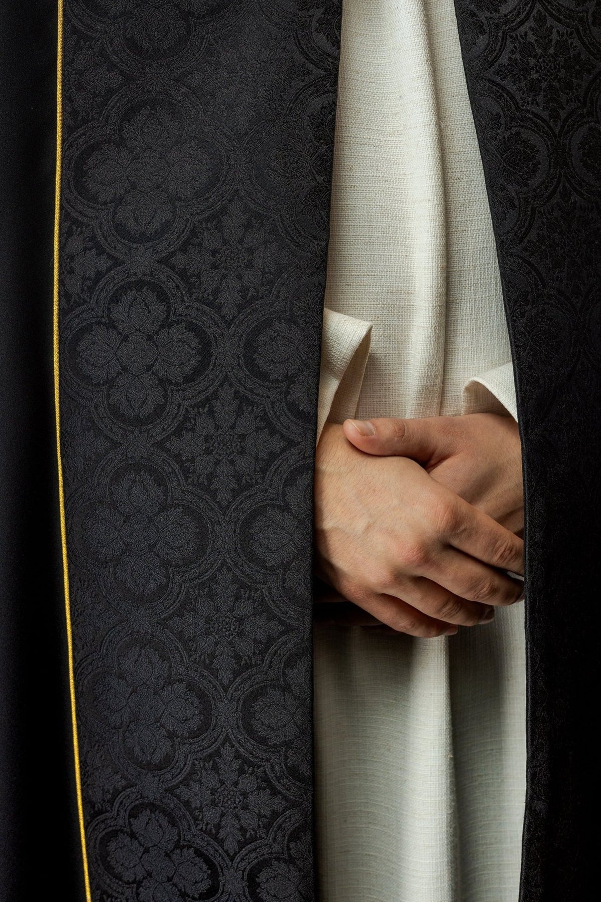 Black cope front detail showing patterned jacquard and gold edging