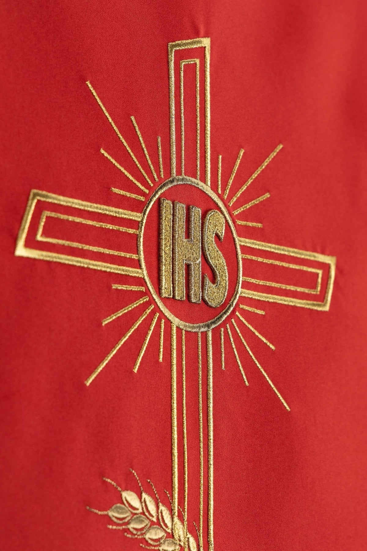 Red church lectern cover close-up showing gold embroidered cross and IHS monogram