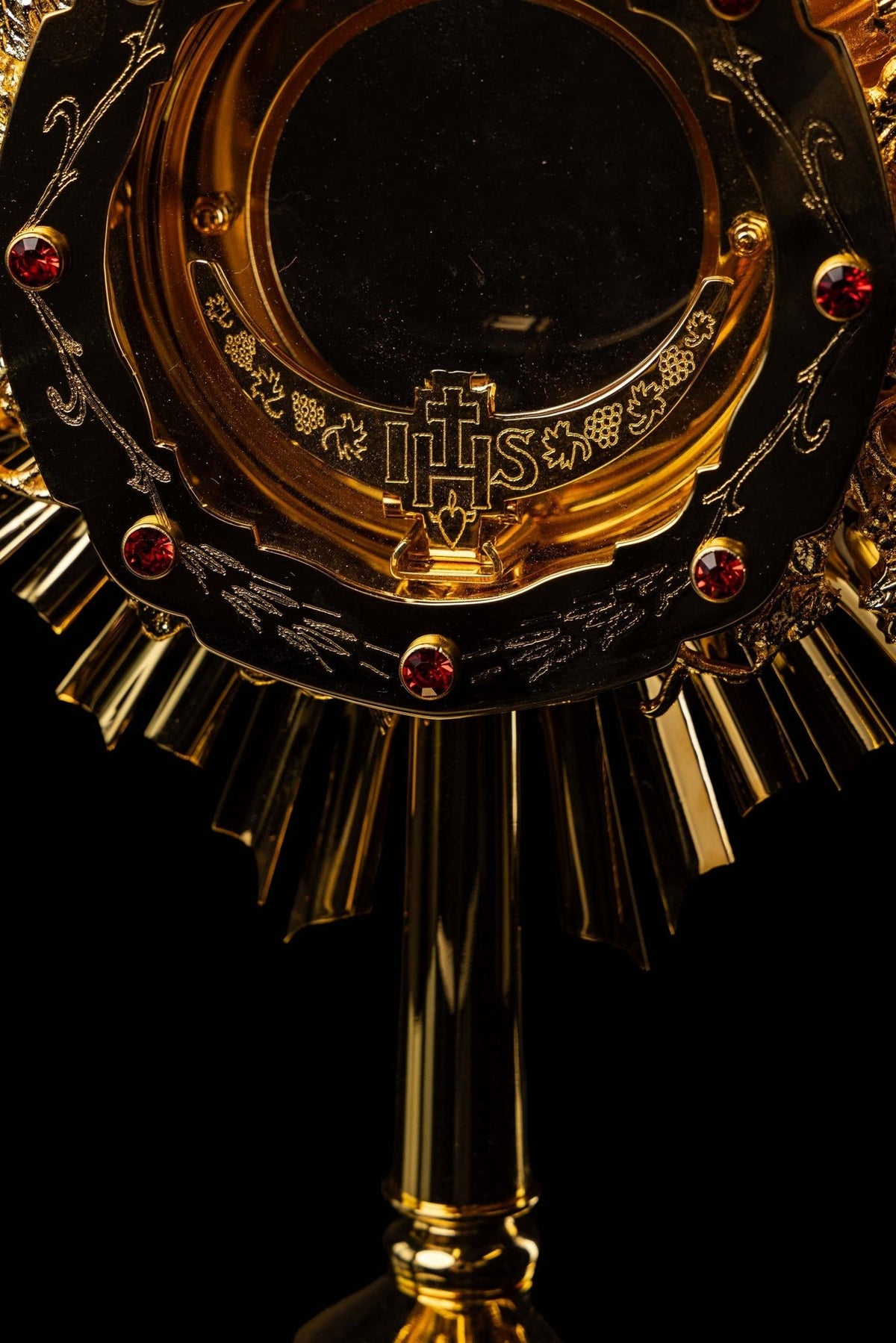 Catholic monstrance close-up showing black enamel ring, red gemstones and IHS Eucharistic symbol
