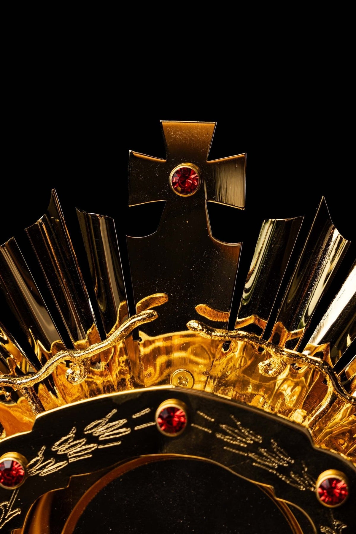 Catholic monstrance close-up of central host opening, engraved grape motifs and red gemstones