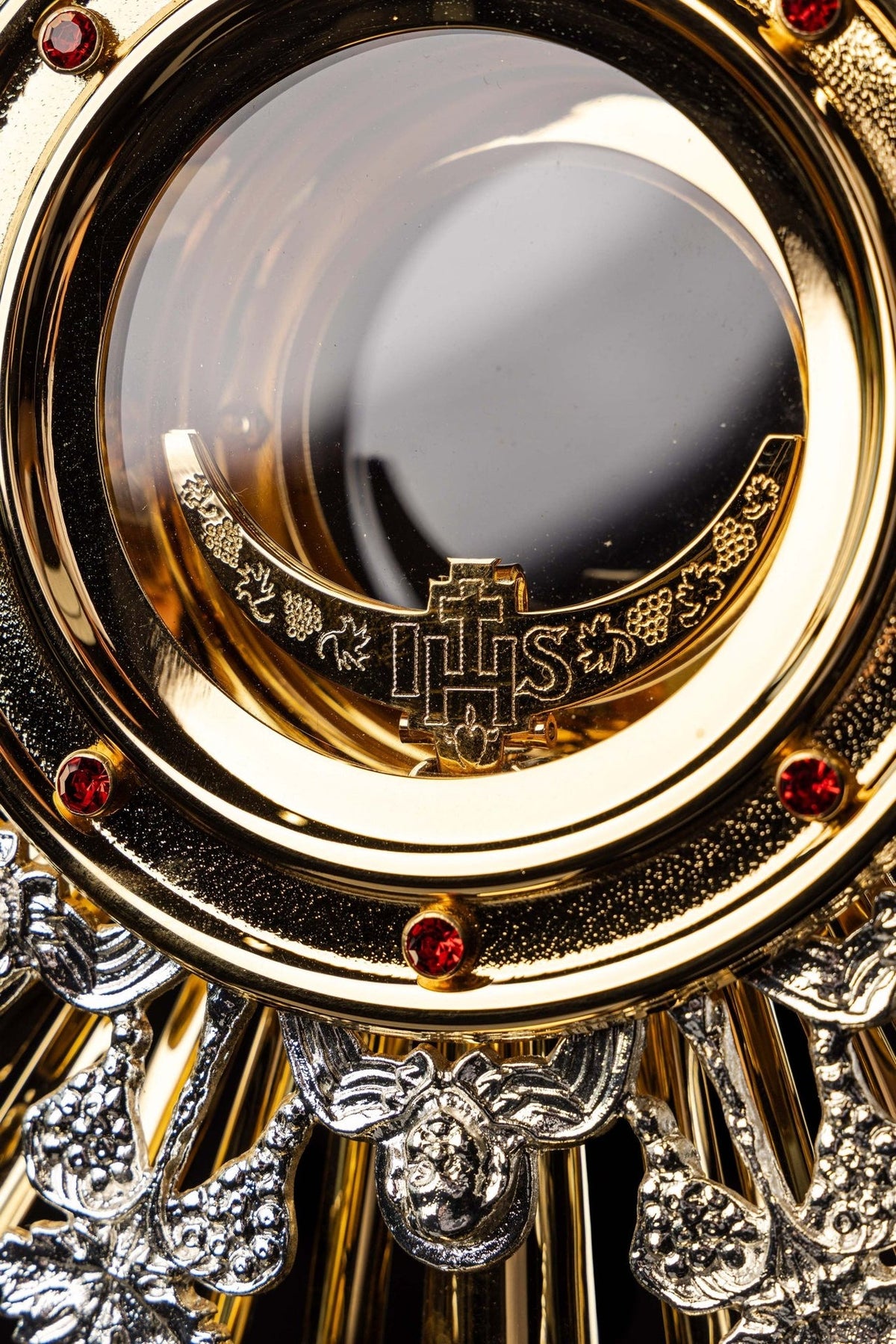 Monstrance close-up of gold host ring with red stones and IHS cross detail