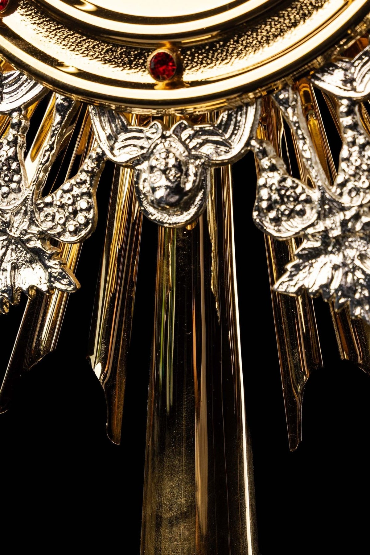 Monstrance close-up of central silver-tone grape ornament and gold rays