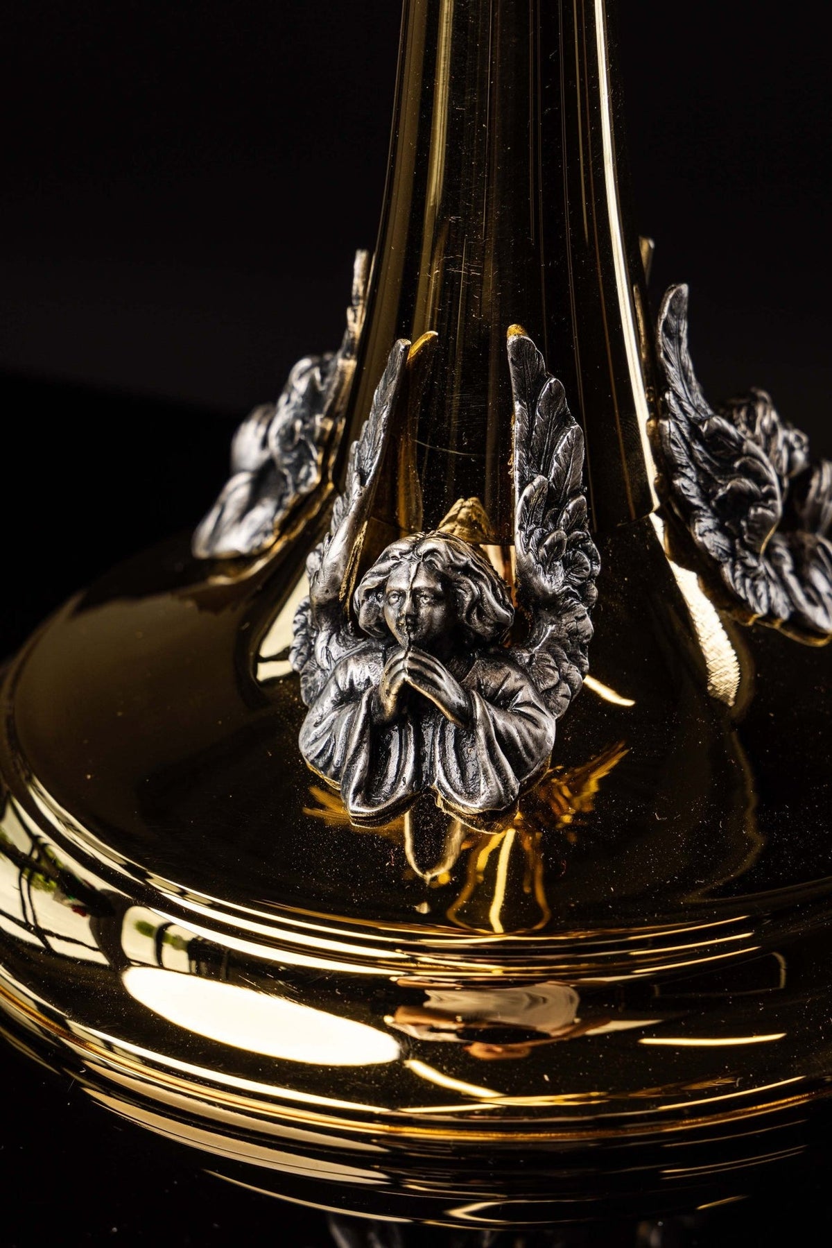 Gold-plated radiant monstrance base close-up with silver praying angel