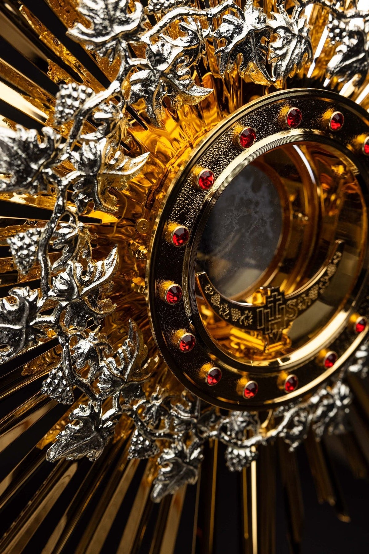 Monstrance close-up showing the gold-plated cross with four red rubies and silver Corpus Christi figure