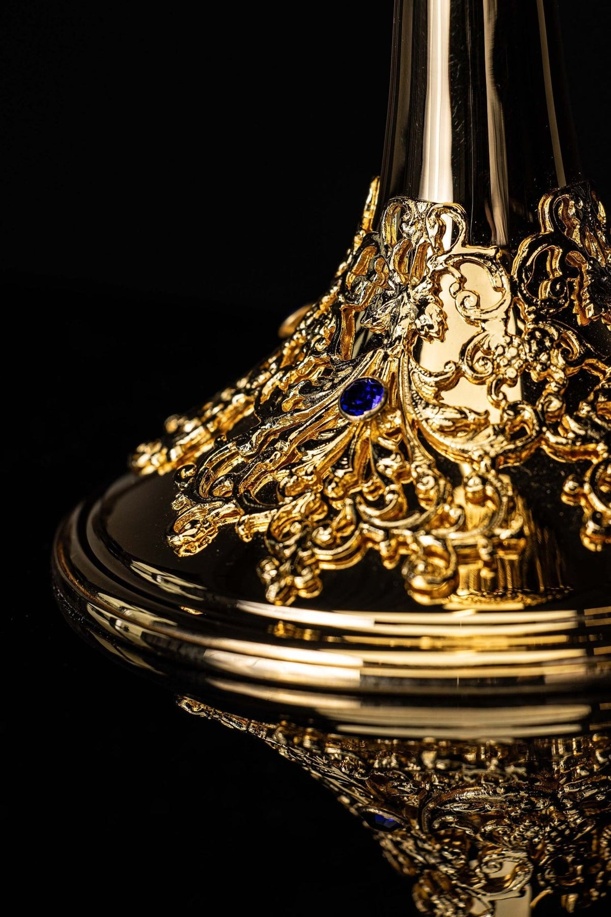 Gold-plated chalice close-up of ornate stem, floral base and blue stones