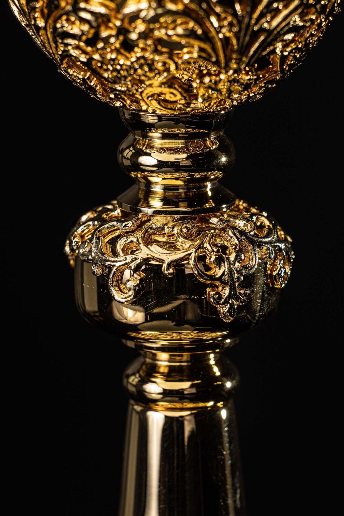 Gold-plated chalice base close-up with raised botanical ornaments and blue stone