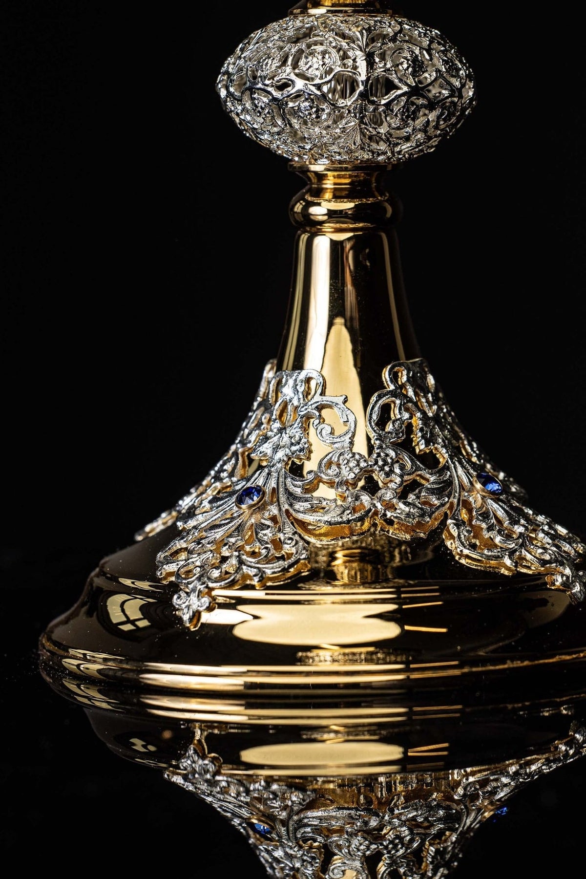 Gold-plated chalice close-up showing ornate base scrollwork and imitation sapphire