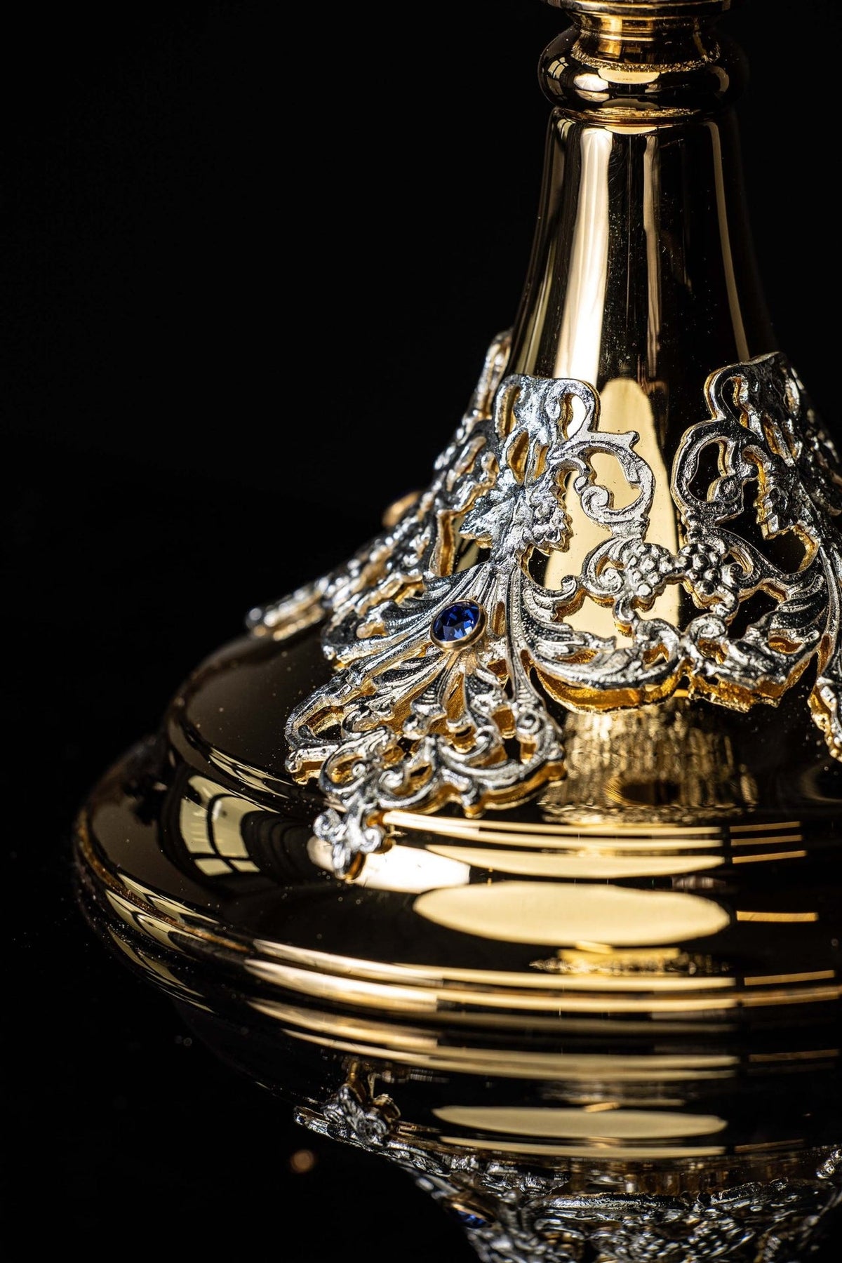 Chalice side close-up showing silver-toned floral decoration and polished gold base