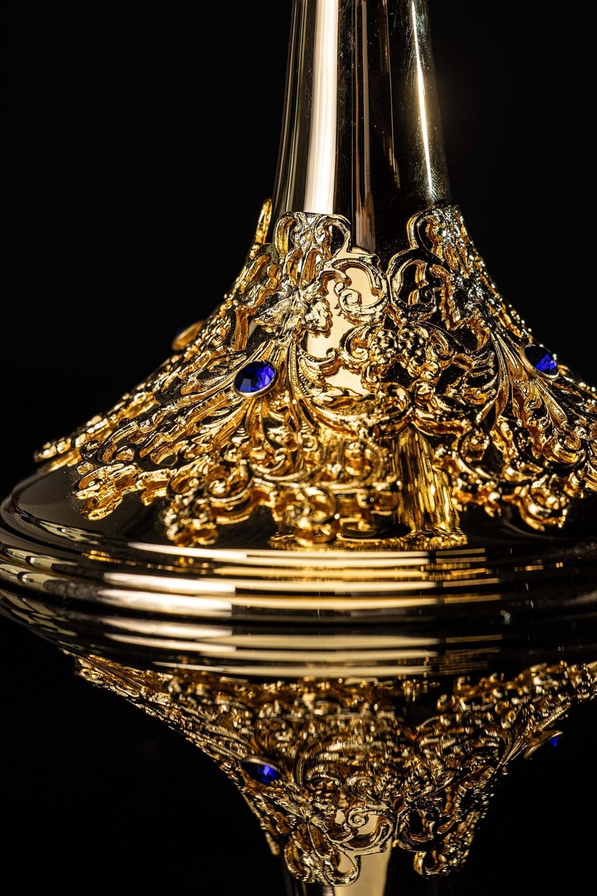 Gold-plated ciborium base close-up with blue sapphires and raised floral scrollwork